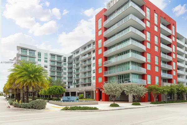 a front view of multi story residential apartment building with yard and traffic signal