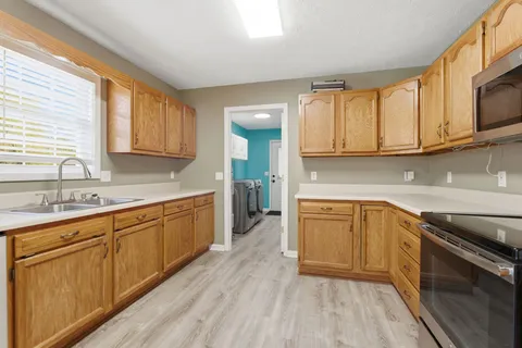a kitchen with granite countertop wooden cabinets stainless steel appliances a sink and a window