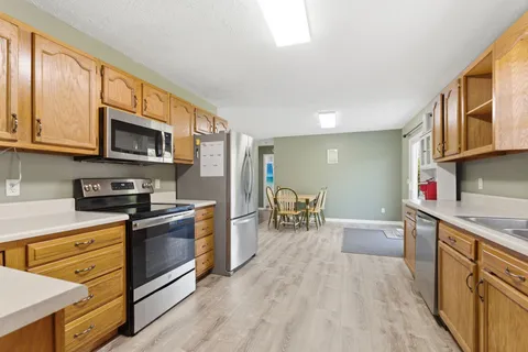 a kitchen with stainless steel appliances granite countertop a stove top oven a sink dishwasher and wooden cabinets with wooden floor