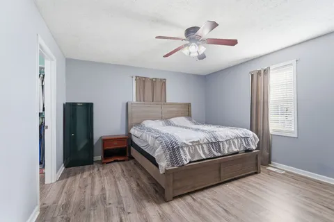 a spacious bedroom with a bed and wooden floor