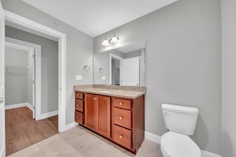 a bathroom with a granite countertop toilet sink and mirror