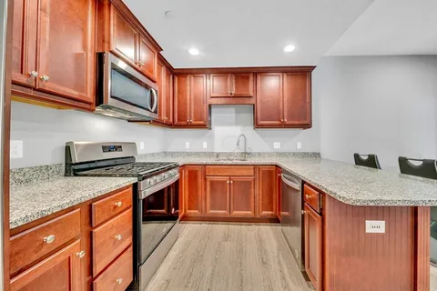 a kitchen with stainless steel appliances granite countertop wooden cabinets a stove top oven a sink and dishwasher
