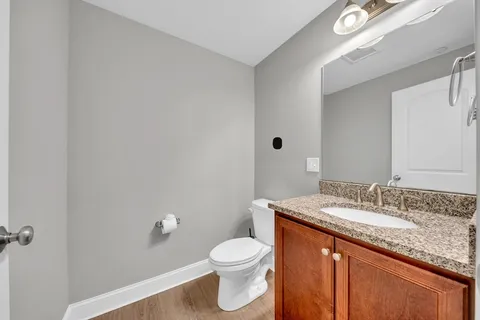a bathroom with a granite countertop sink a toilet and a mirror