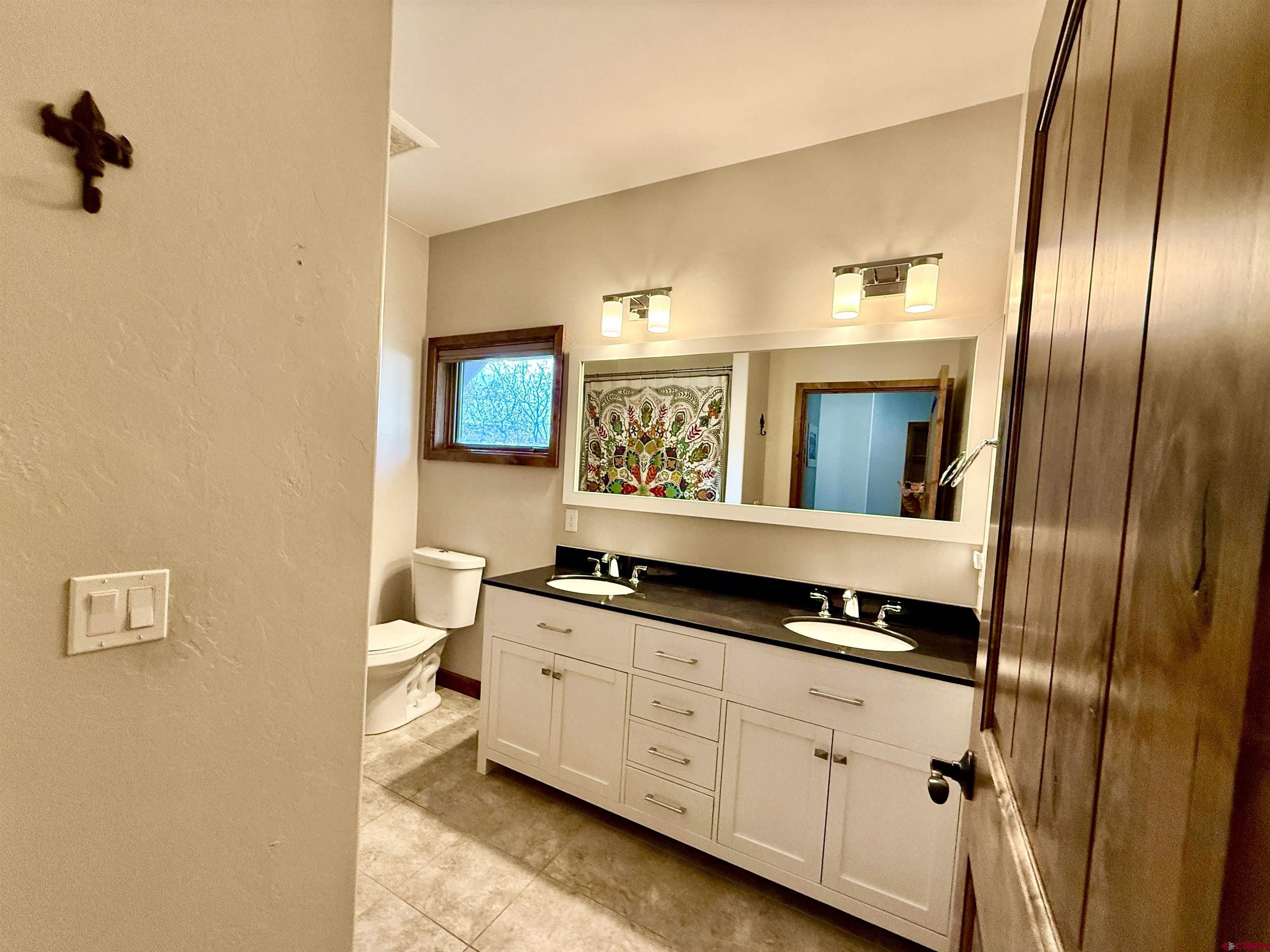 592 South Badger Trail Ridgway, CO 81432 - Photo 14 of 29 a spacious bathroom with a granite countertop sink a mirror and a toilet