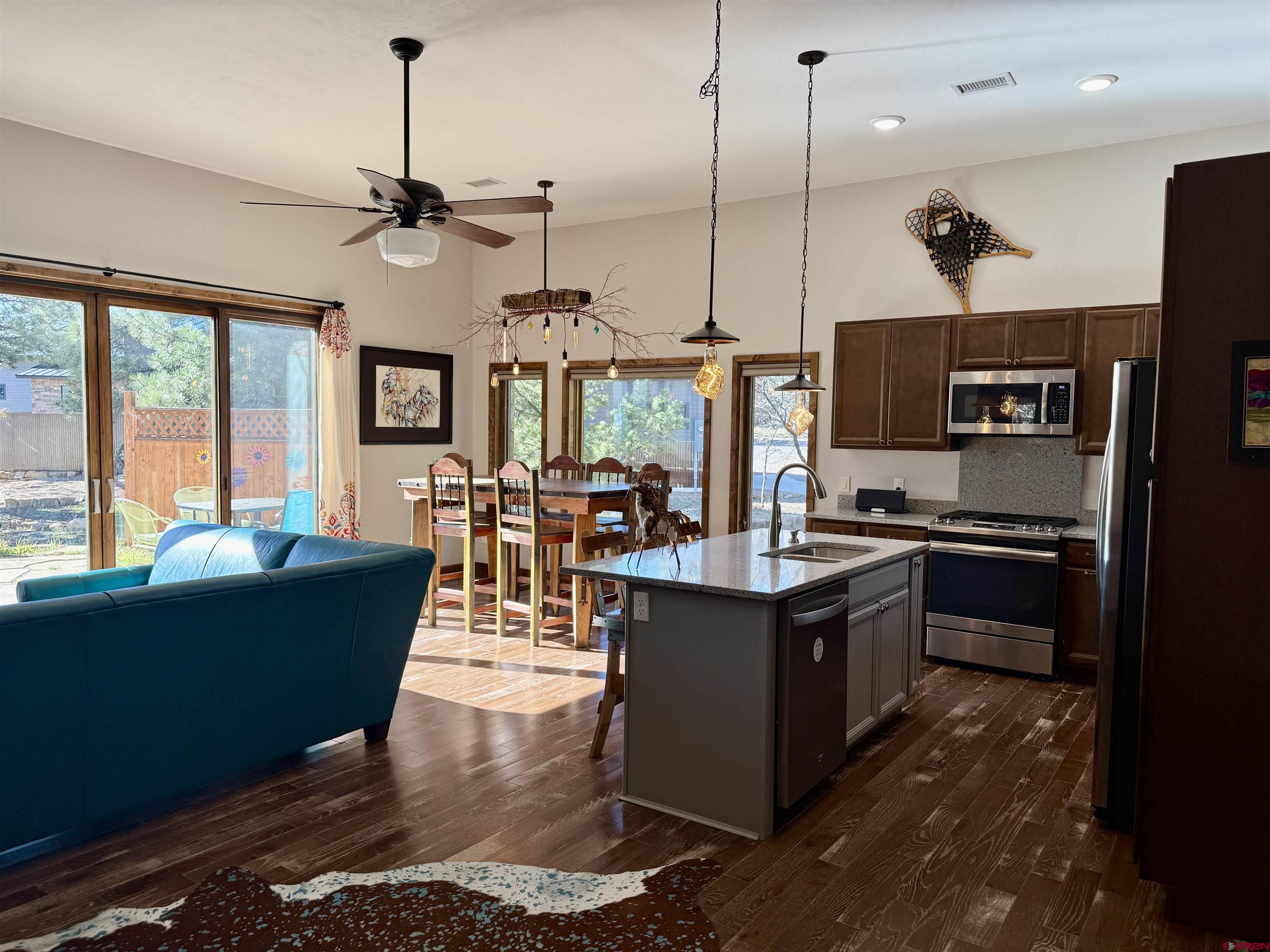 592 South Badger Trail Ridgway, CO 81432 - Photo 6 of 29 a kitchen with stainless steel appliances granite countertop a stove top oven a refrigerator a sink a dining table and chairs with wooden floor
