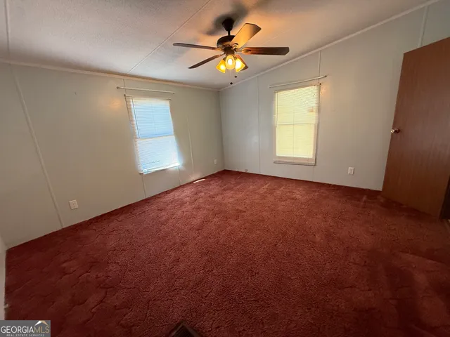 an empty room with windows and chandelier fan