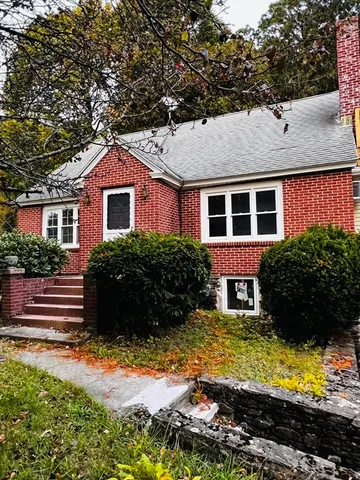 a view of a house with a yard plants and large tree