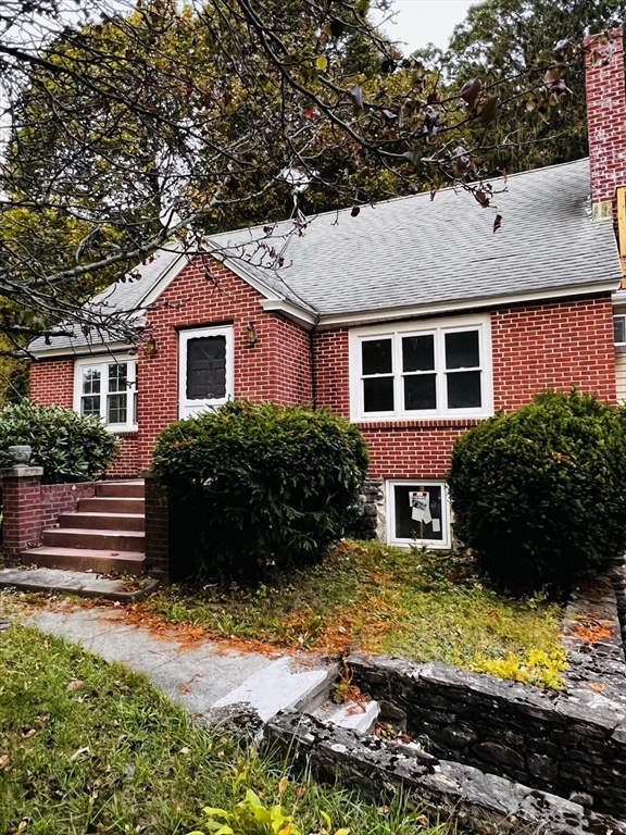a view of a house with a yard plants and large tree