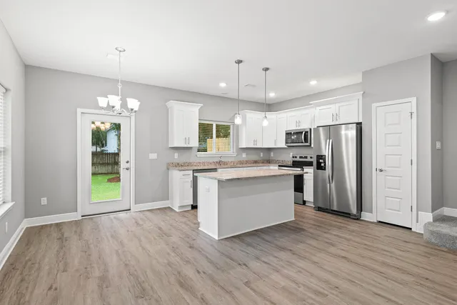 a kitchen with kitchen island wooden floors white cabinets and stainless steel appliances