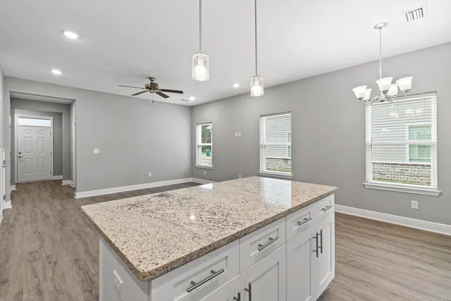a view of a kitchen island a sink wooden floor and a chandelier