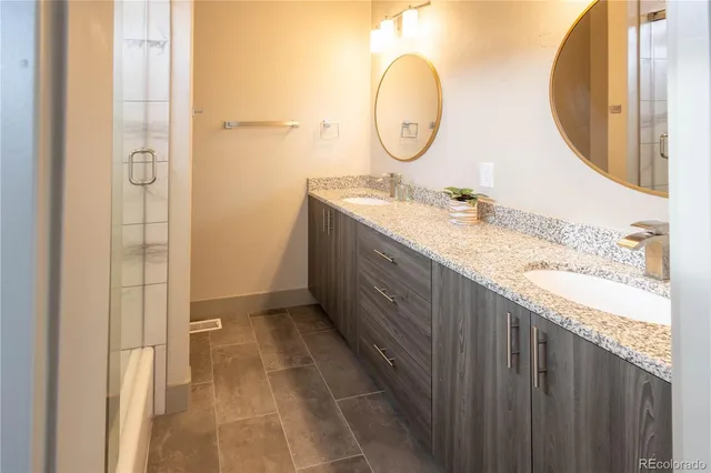 a bathroom with a granite countertop sink a mirror and a shower
