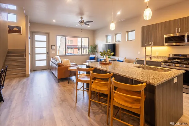 a kitchen with stainless steel appliances granite countertop a stove a refrigerator a kitchen island a stove and a wooden floors