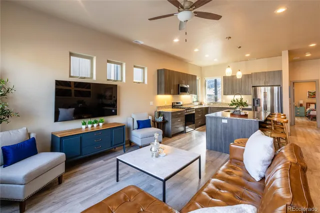 a living room with stainless steel appliances furniture and a flat screen tv