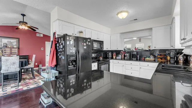 a large kitchen with stainless steel appliances a refrigerator a stove a sink dishwasher a dining table and chairs with wooden floor