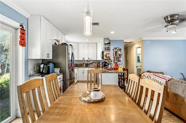 a kitchen with stainless steel appliances kitchen island granite countertop a refrigerator a stove a sink dishwasher and a dining table with wooden floor