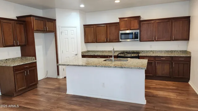 a kitchen with stainless steel appliances granite countertop wooden cabinets a refrigerator and a sink