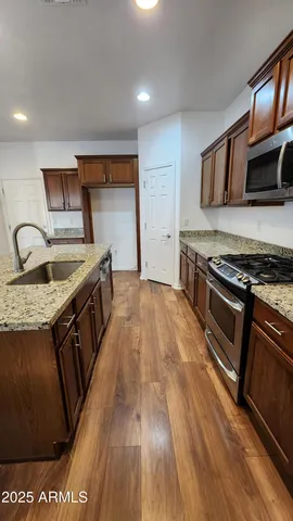 a kitchen with stainless steel appliances granite countertop a sink a stove and a wooden floors