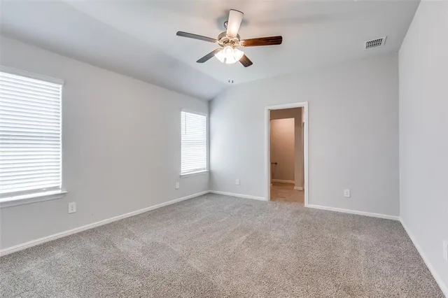 an empty room with chandelier fan and windows