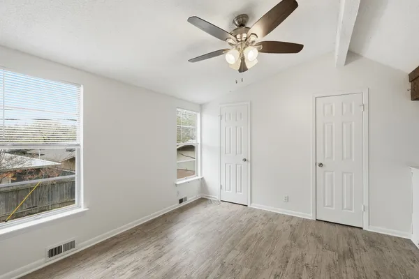 an empty room with wooden floor and windows
