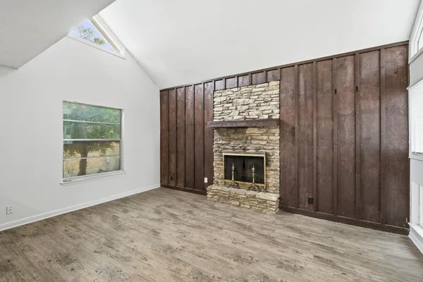 an empty room with windows and fireplace
