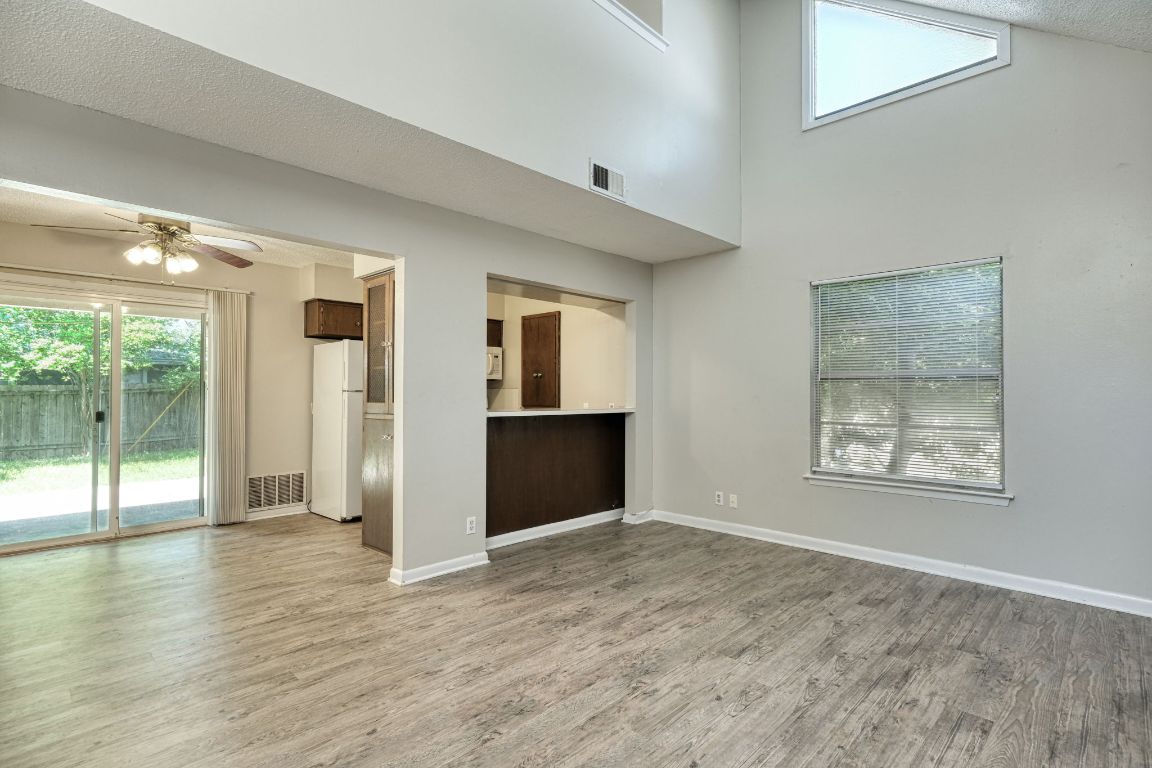 2711 St Edwards Circle, Unit 1 Austin, TX 78704 - Photo 5 of 14 Unfurnished living room with a textured ceiling, light wood-style flooring, ceiling fan, and a high ceiling