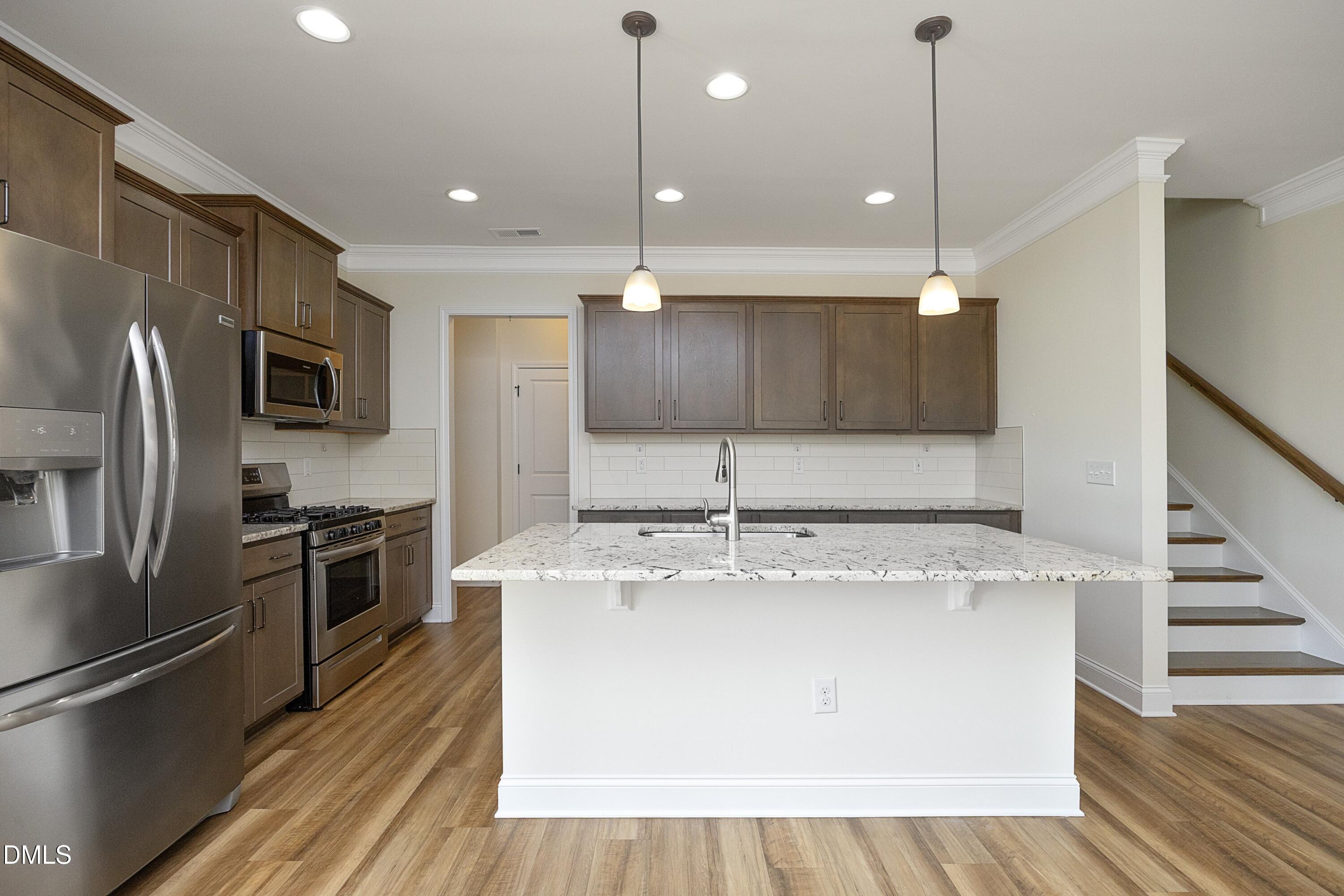 824 Country Downs Road Wake Forest, NC 27587 - Photo 3 of 41 a kitchen with kitchen island stainless steel appliances a stove refrigerator sink and microwave