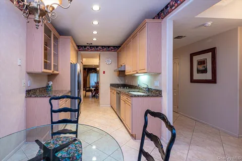 a kitchen with granite countertop lots of wooden furniture and stainless steel appliances