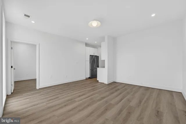 a view of an empty room with wooden floor and closet