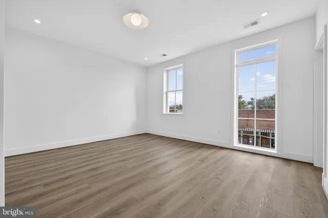 an empty room with wooden floor and windows