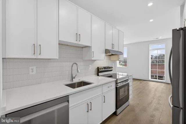 a kitchen with stainless steel appliances granite countertop a sink a stove and white cabinets