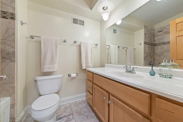 a bathroom with a granite countertop toilet sink and a mirror