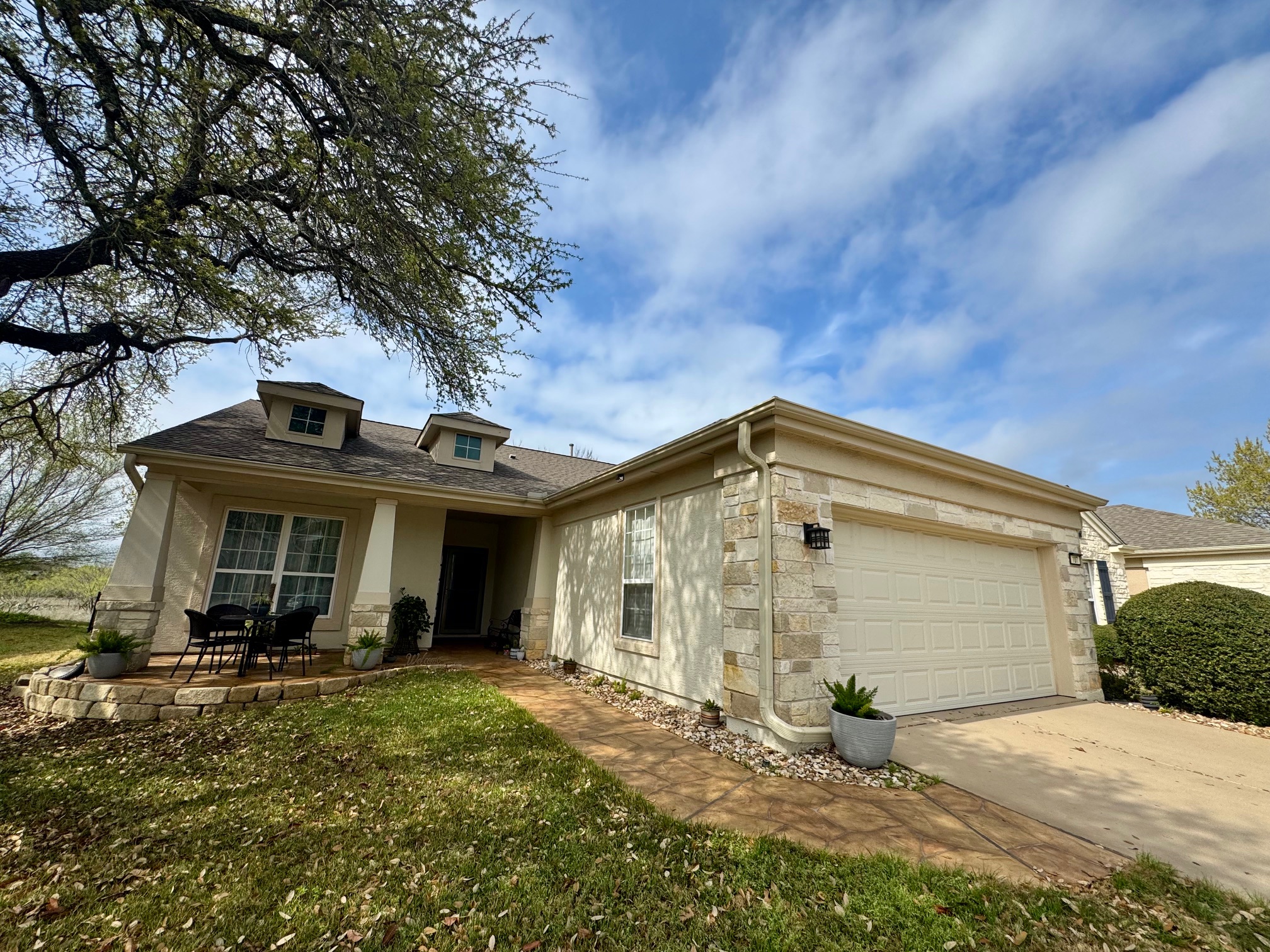 View of front of house featuring stone siding, an attached garage, concrete driveway, and a front yard