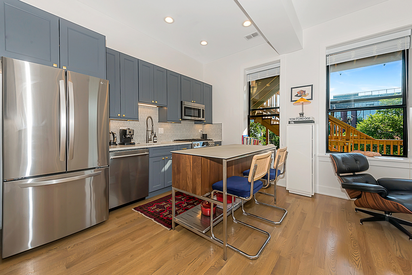 3517 North Reta Avenue, Unit 3R Chicago, IL 60657 - Photo 3 of 9 a kitchen with stainless steel appliances a refrigerator a stove a sink dishwasher and a dining table with wooden floor