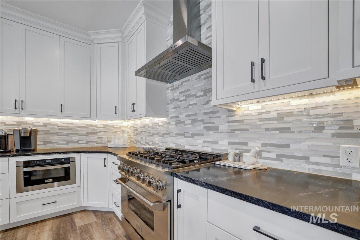 2078 Red Rock Way Twin Falls, ID 83301 - Photo 2 of 49 Kitchen with wall chimney exhaust hood, appliances with stainless steel finishes, white cabinets, and decorative backsplash