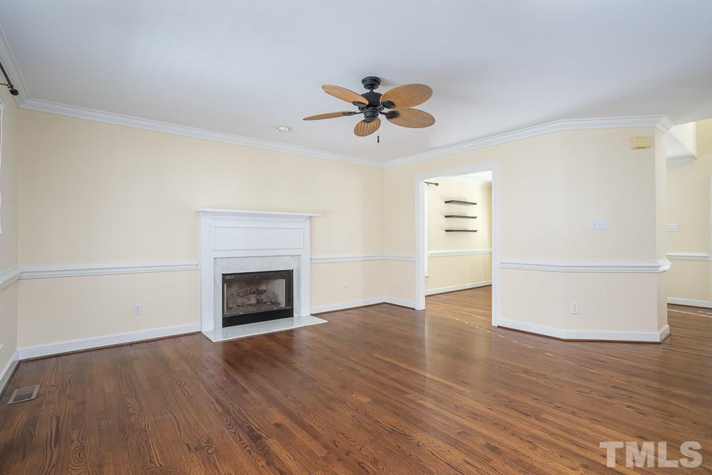 2409 Dahlgreen Road Raleigh, NC 27615 - Photo 8 of 30 an empty room with wooden floor a ceiling fan a fireplace and windows
