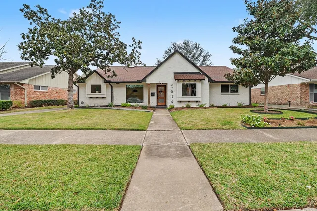 a view of a yard in front of a house with a large tree