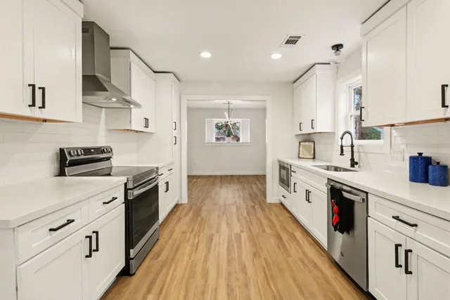 a large kitchen with stainless steel appliances granite countertop a lot of counter space and wooden floors