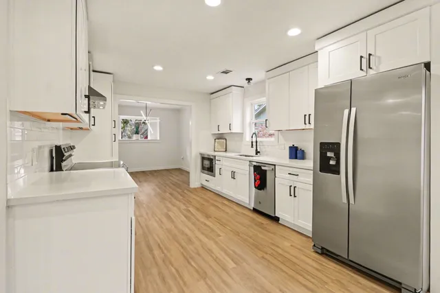 a kitchen with stainless steel appliances a refrigerator sink and white cabinets