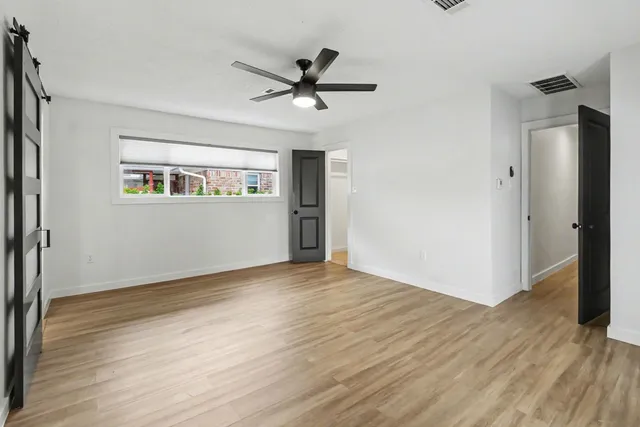 an empty room with wooden floor a ceiling fan and windows