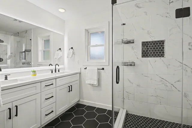 a spacious bathroom with a double vanity sink a mirror and a shower