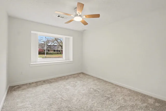 an empty room with a window and a ceiling fan