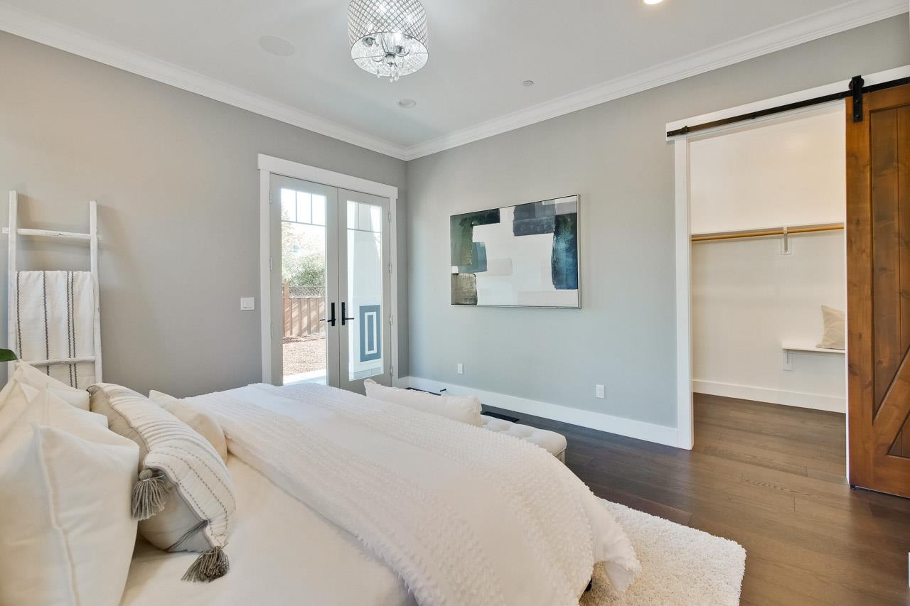 10326 Prune Tree Lane Cupertino, CA 95014 - Photo 79 of 95 a bedroom with a large bed and a chandelier