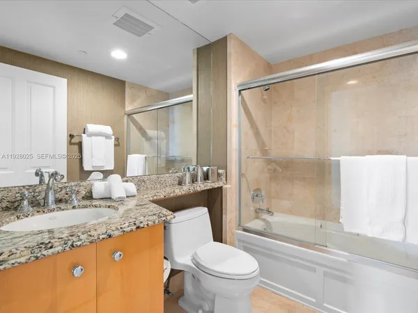 a bathroom with a granite countertop sink toilet and shower
