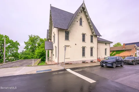 a view of a white house with large windows and a small yard