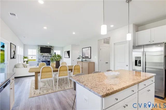 a kitchen with stainless steel appliances kitchen island granite countertop a table chairs and a refrigerator