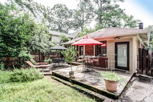 a view of a patio with chairs and a table and chairs under an umbrella