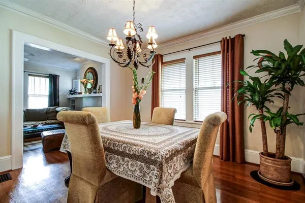 a dining room with furniture potted plants a chandelier and wooden floor