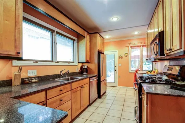 a kitchen with stainless steel appliances granite countertop a sink a stove counter space and cabinets
