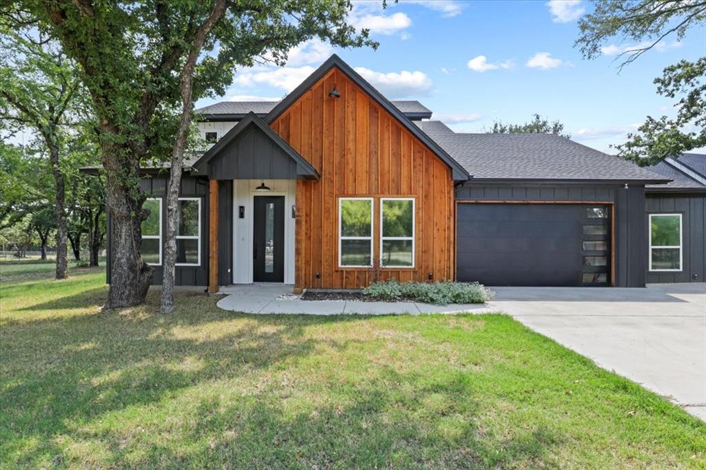 a view of yellow house with a big yard and large tree