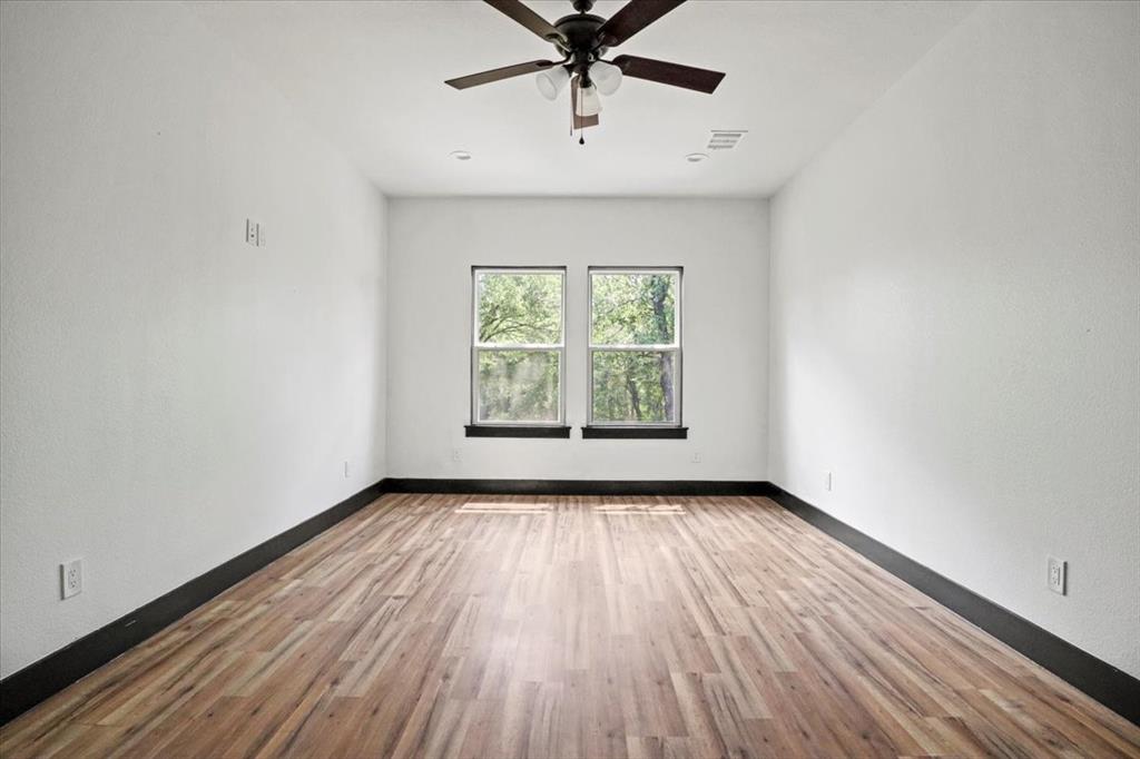1791 JE Woody Road Springtown, TX 76082 - Photo 27 of 33 an empty room with wooden floor chandelier fan and windows